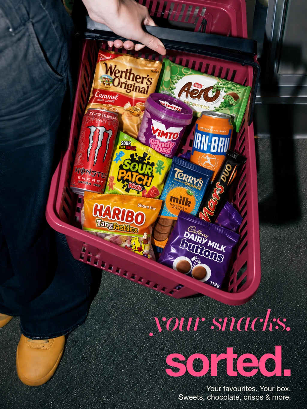 Your snacks, sorted: assorted packaged snacks in a pink shopping basket. Illustrative selection; contents vary.